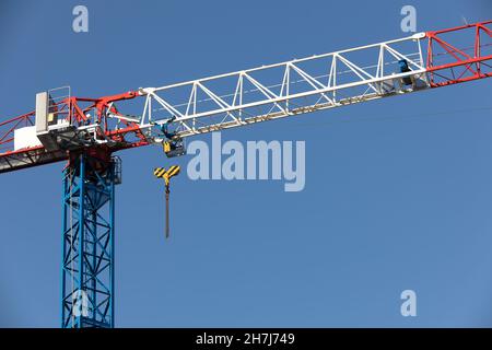 blue, white and red construction crane against the sky Stock Photo