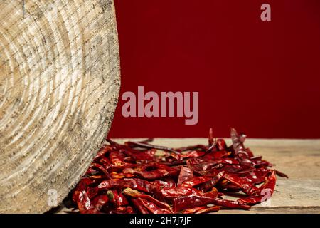 dried hot peppers on wooden table in front of red background Stock Photo