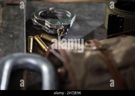 On the crate are eating handcuffs three empty rifle cartridges and a military belt. Stock Photo