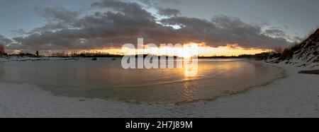 Sunset over a frozen lake. Winter landscape. Leningrad region. Stock Photo
