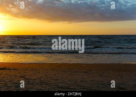 Between the clouds and the sea, the sky is lit up by the light of the setting sun in Kolobrzeg , Poland Stock Photo
