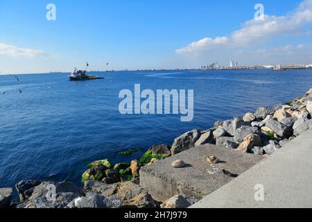 Istanbul, Turkey - November 2021: Fishing boat surrounded by seagulls sailing along the Yenikapi promenade. Stock Photo