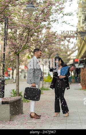 Two business people are talking under the falling flower leafs Stock Photo