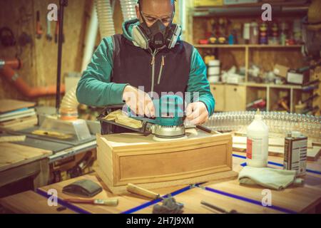 man uses an orbital sander in his workshop. Stock Photo