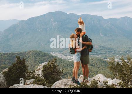 Couple kissing outdoor family hiking with child travel in mountains active vacations mother and father parents backpacking together with baby Stock Photo