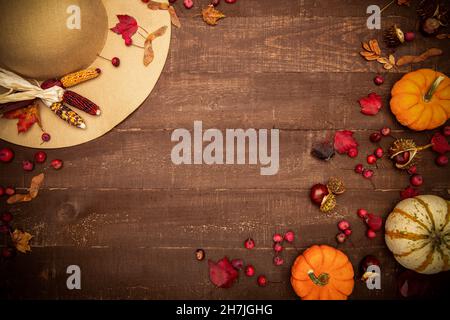 Beige hat with fall elements - mini pumpkins, chestnuts, leaves, corn, crab apples on a rustic wooden background. Fall concept. Flat lay, top view, co Stock Photo