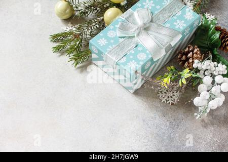Christmas or New Year holidays composition layout. Fir tree snow branch, Christmas present and decoration on a stone tabletop. Copy space. Stock Photo