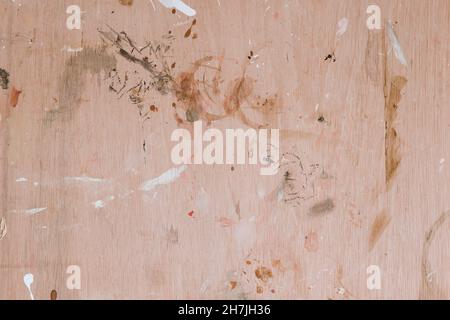 Colorful paint splashes on wooden board. Flat lay, top view. Abstract background from a painter workshop. White, brown and grey colors on plywood Stock Photo