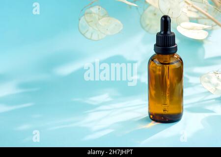Brown glass bottle with a pipette on a blue background. Glass bottle without label, cosmetic products composition with place for text. Skin care, set Stock Photo
