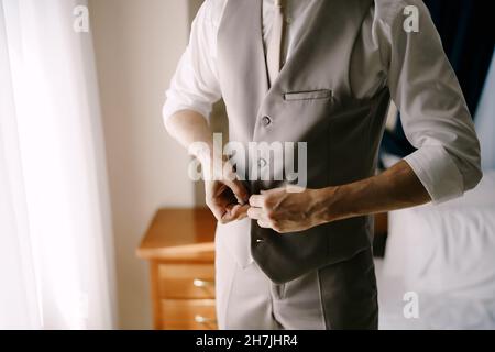 Man in a shirt buttoning the buttons on his vest. Close-up Stock Photo