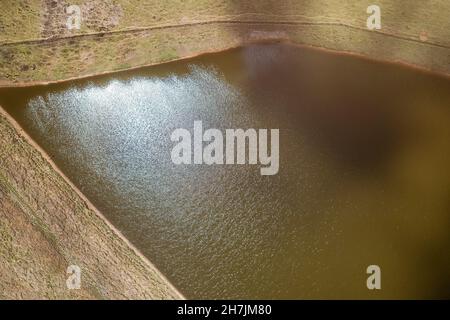 Sun shining brightly on the colored water of a small country dam Stock Photo