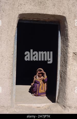 A Baluch girl sits at the doorstep of their mud home, at the village of Sultan Koth, in Sibi district of the Beluchistan province in Pakistan. The Sib Stock Photo