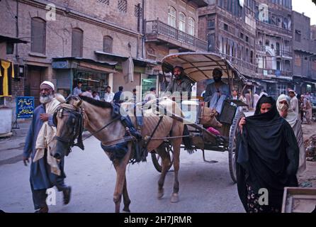 Using a traditional horse cart, a man transports his passengers and their luggage, throughn the Kissa Khuwani Bazaar, in Peshawar, the capital of Nort Stock Photo