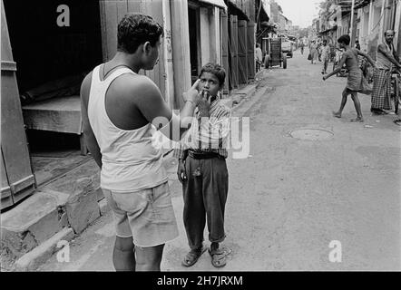 Standing in an alley in Kolkata, a man scolds a young boy. India. Stock Photo