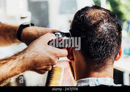 Closeup of trimmer machine. Process of trimming of hair in barber shop. Stock Photo