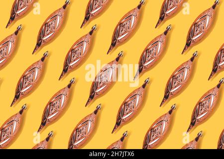 Repetitive pattern made of gold colored Christmas baubles on a yellow background. Stock Photo