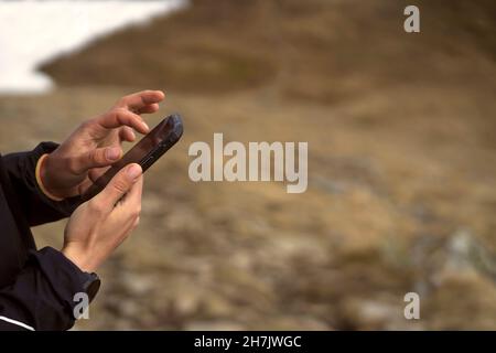 Man holds a smartphone in his hands and looks at a map,  Stock Photo