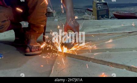 A photo of a worker who is using a grinder in Asia Stock Photo