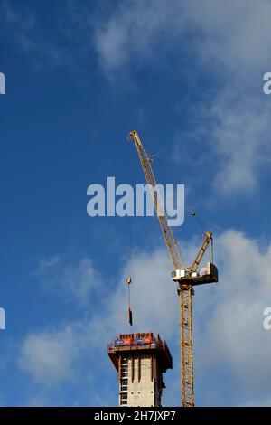 Cardiff, Wales - November 2017: Tower crane lifting building materials to the top of an elevator shaft being constructed for a new office development. Stock Photo