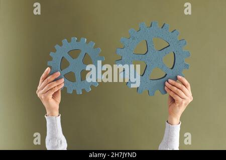 Woman connecting two gear wheels to show the concept of innovation and integration Stock Photo