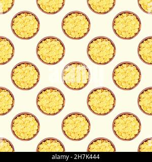 Top view flat lay yellow corn flakes in a round wooden bowl repeat seamless pattern on light background. Stock Photo