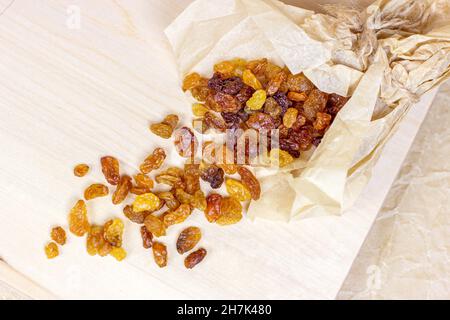 Top view of brown raisins (dried yellow grape) on light wooden background. Stock Photo