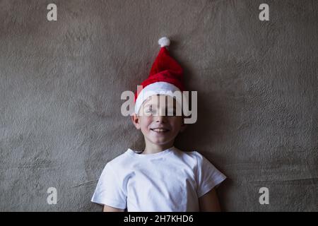 High angle view boy in a christmas hat smiling while lying on bed Stock Photo