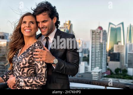 Young hispanic couple hugging embracing at a roof top in panama city. Sunset Stock Photo