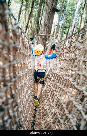 Boy walks across a mesh bridge. Back view Stock Photo