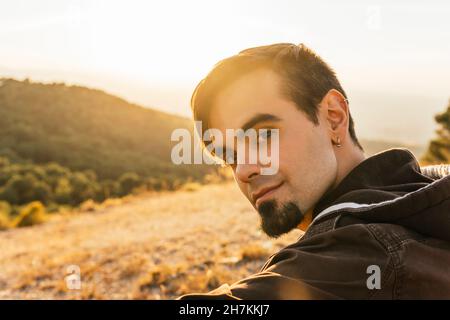 Young man looking over shoulder during sunny day Stock Photo
