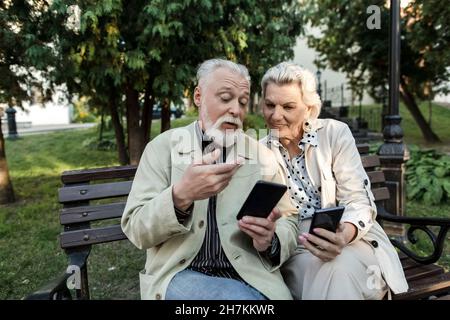 Couple using smart phones while sitting on bench Stock Photo