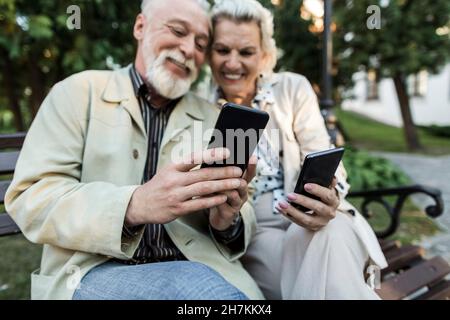 Couple using smart phone while sitting on bench Stock Photo