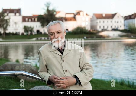 Mature man with hands clasped leaning on railing Stock Photo