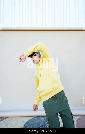 Young man dancing in front of beige backdrop Stock Photo