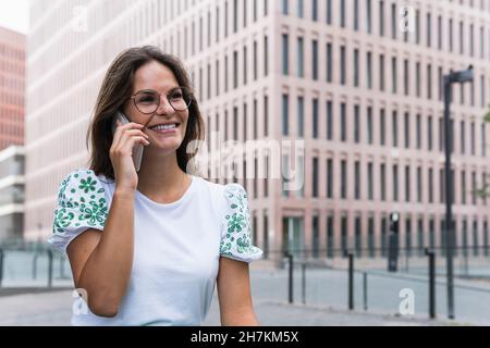 Happy young working woman while talking on mobile phone Stock Photo