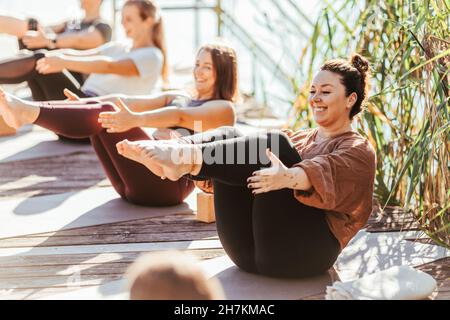 Smiling women practicing yoga on exercise mat Stock Photo