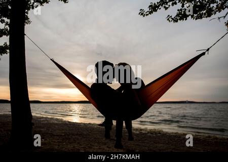 Couple relaxing in hammock during sunset Stock Photo