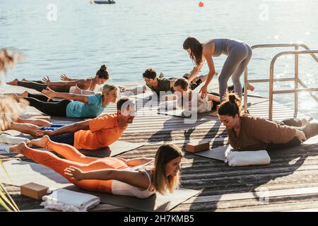 Female instructor guiding woman doing yoga during class Stock Photo
