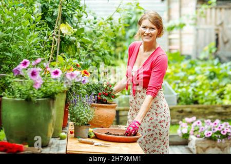 Smiling woman putting soil in flower pot Stock Photo