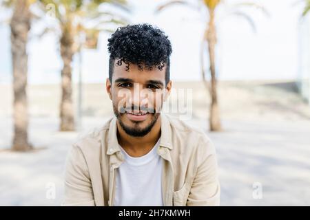 Smiling young bearded man with curly hair Stock Photo