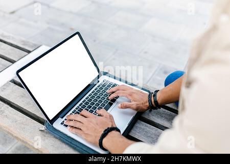 Young man using laptop on bench Stock Photo