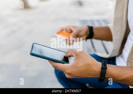 Man with credit card doing online shopping through smart phone Stock Photo