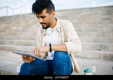 Man using digital tablet while sitting on steps Stock Photo