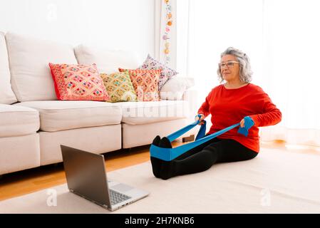 Woman stretching legs with resistance band at home Stock Photo