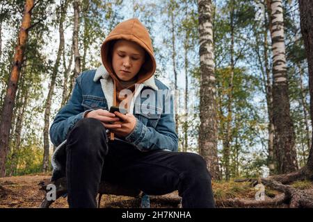Boy using smart phone in forest Stock Photo