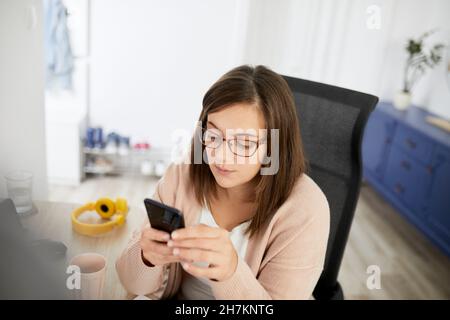 Female freelancer using smart phone while working at home Stock Photo