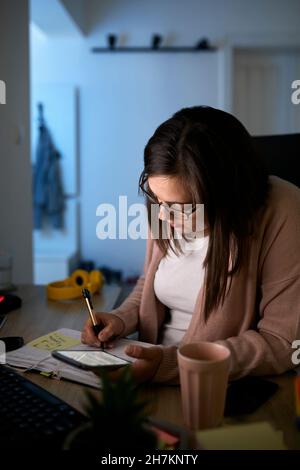 Businesswoman working on home finances at night Stock Photo