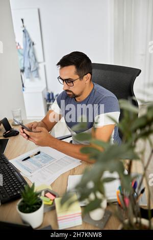 Businessman using smart phone while working at home office Stock Photo