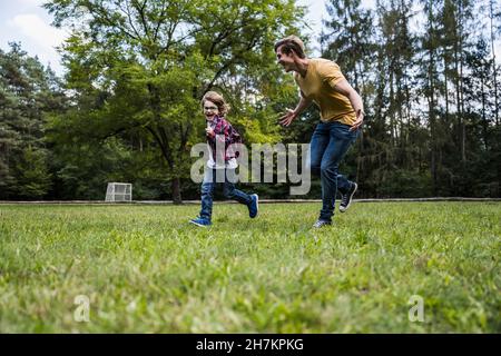 Happy son playing with father on grass Stock Photo