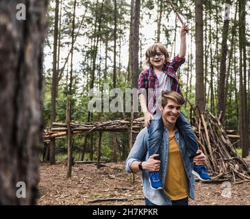 Happy man carrying son on shoulders in forest Stock Photo